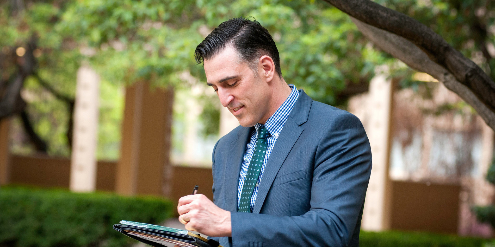 Michael Renzi looking down while signing a paper