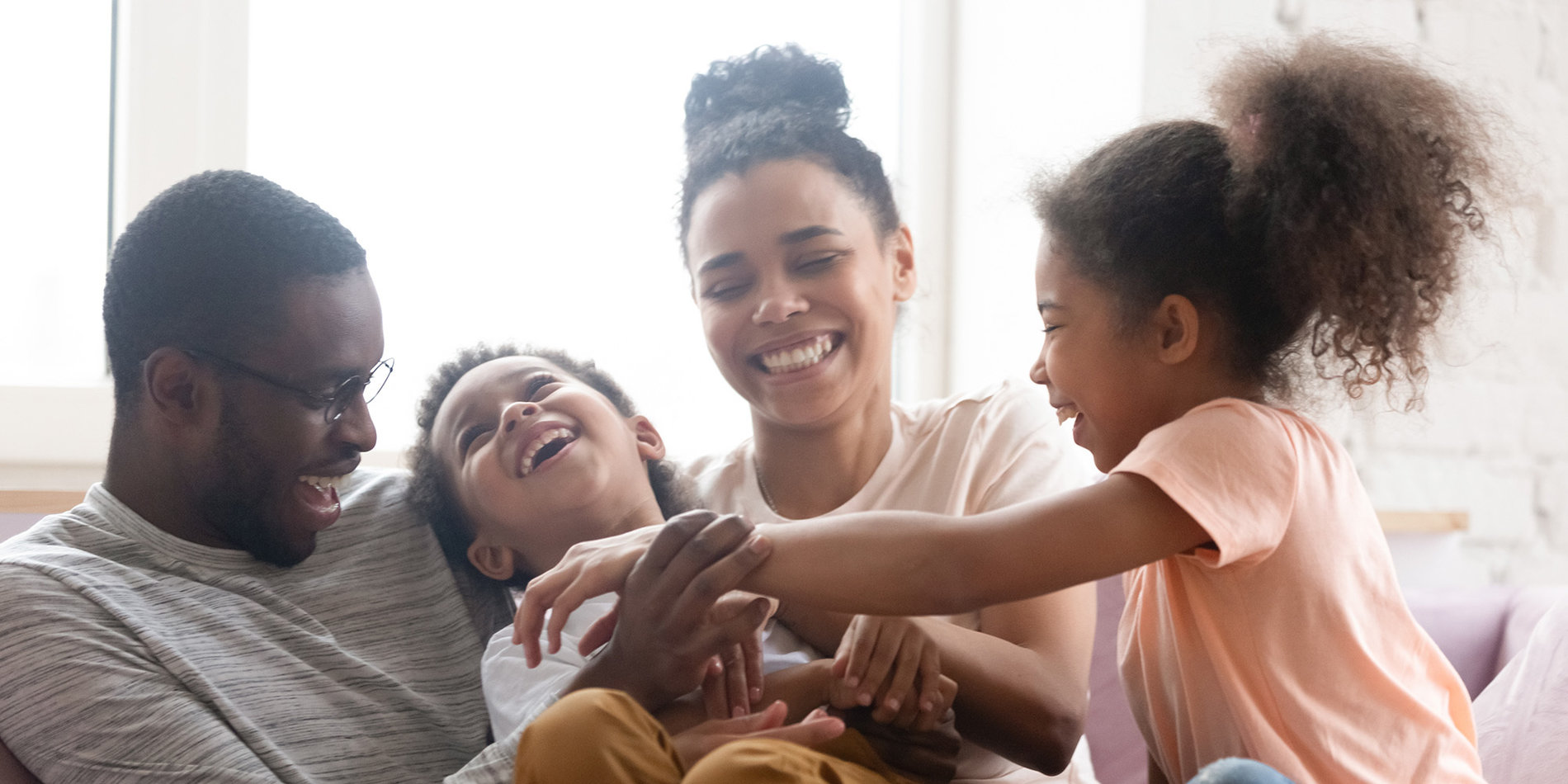 Male and female parents smiling and playing with their two kids