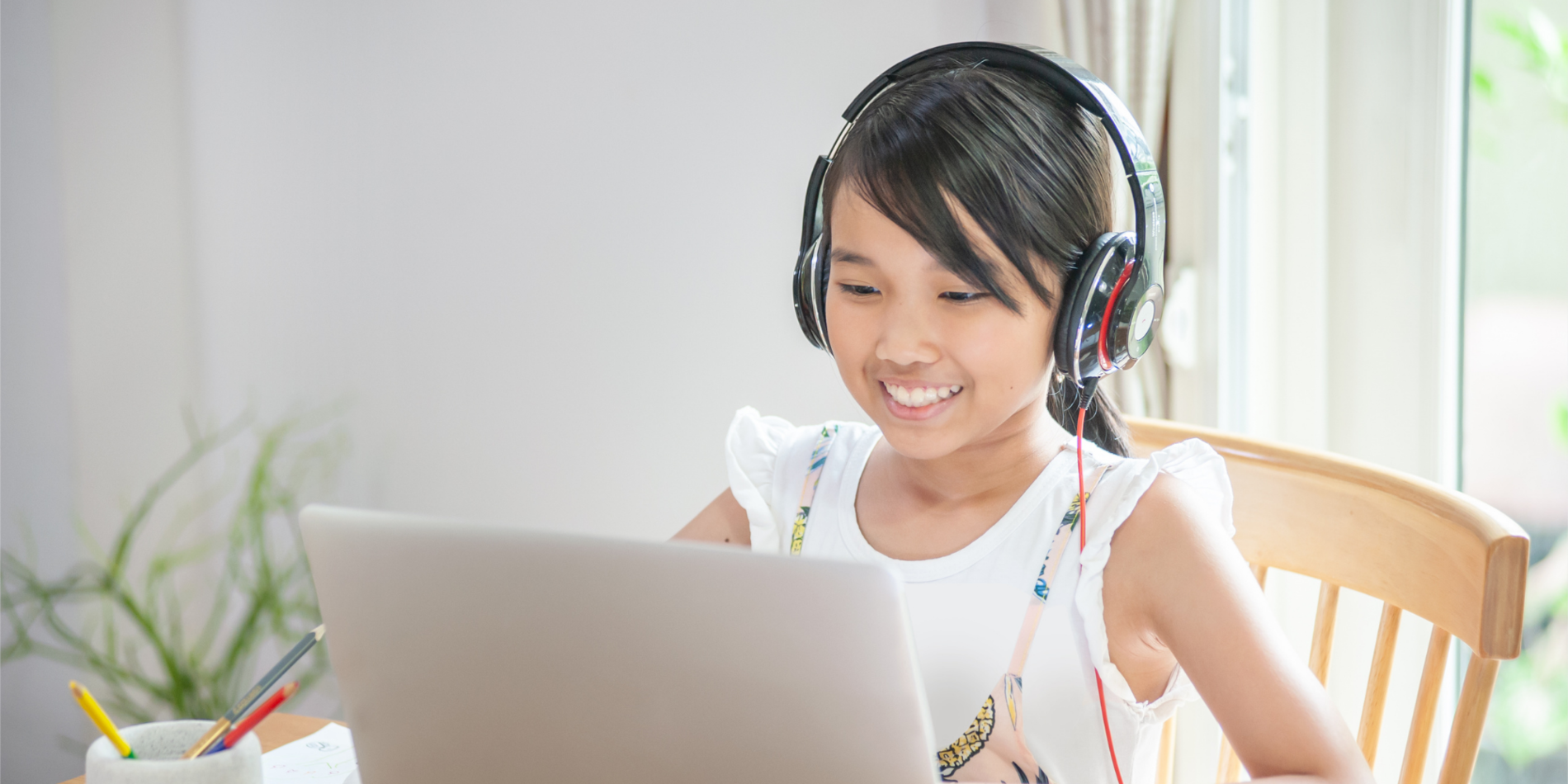 Smiling young girl using laptop to learn online at home