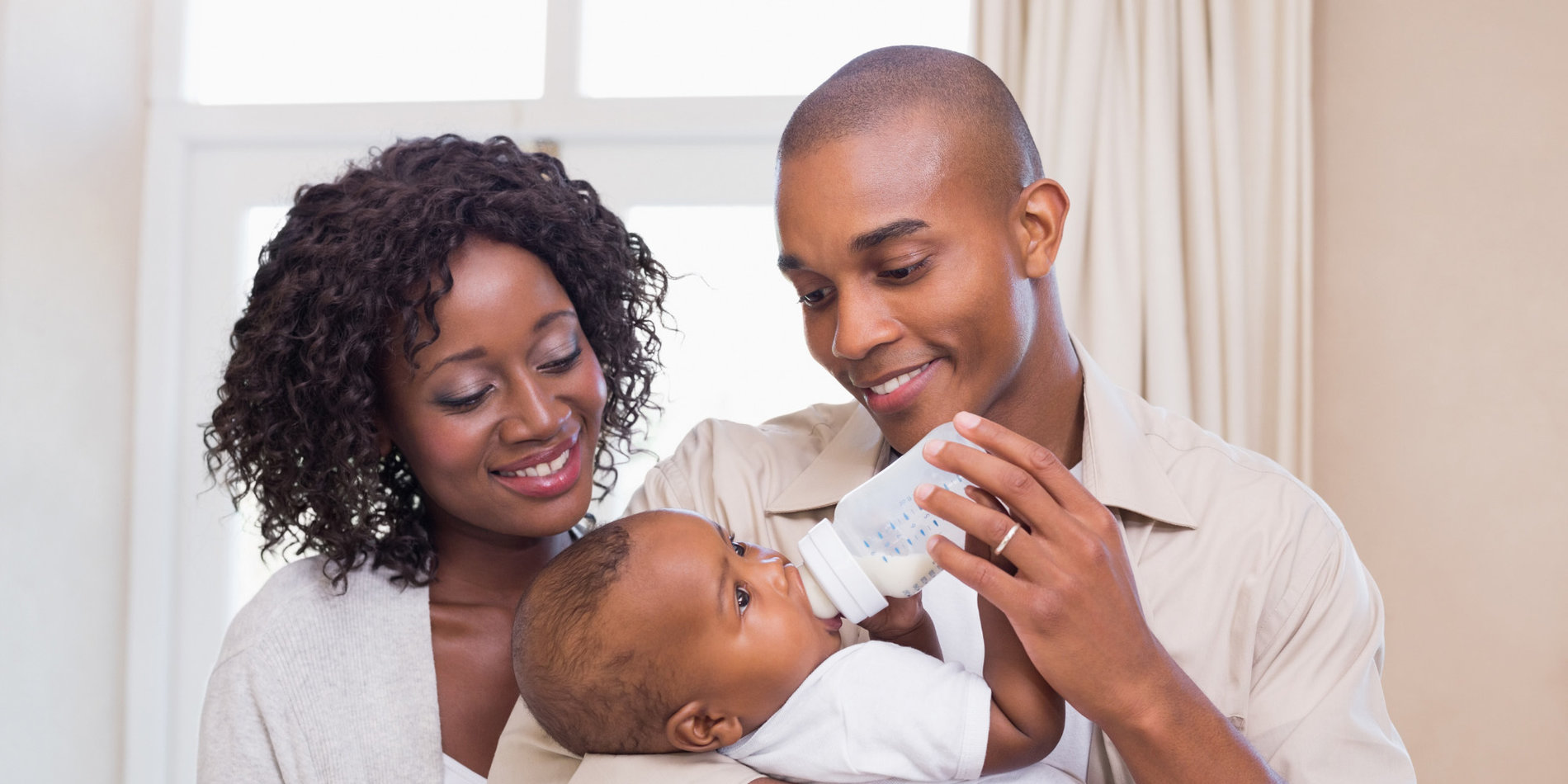 Happy parents feeding their baby boy a bottle