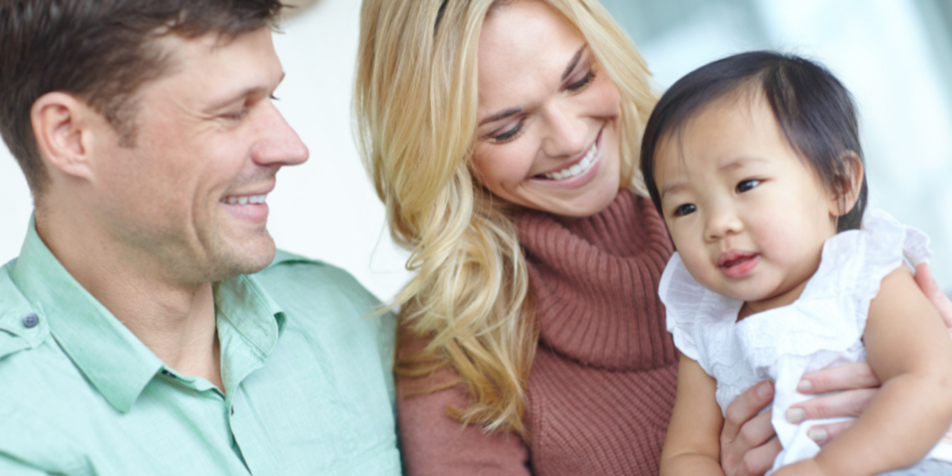 White couple holding their adopted asian baby