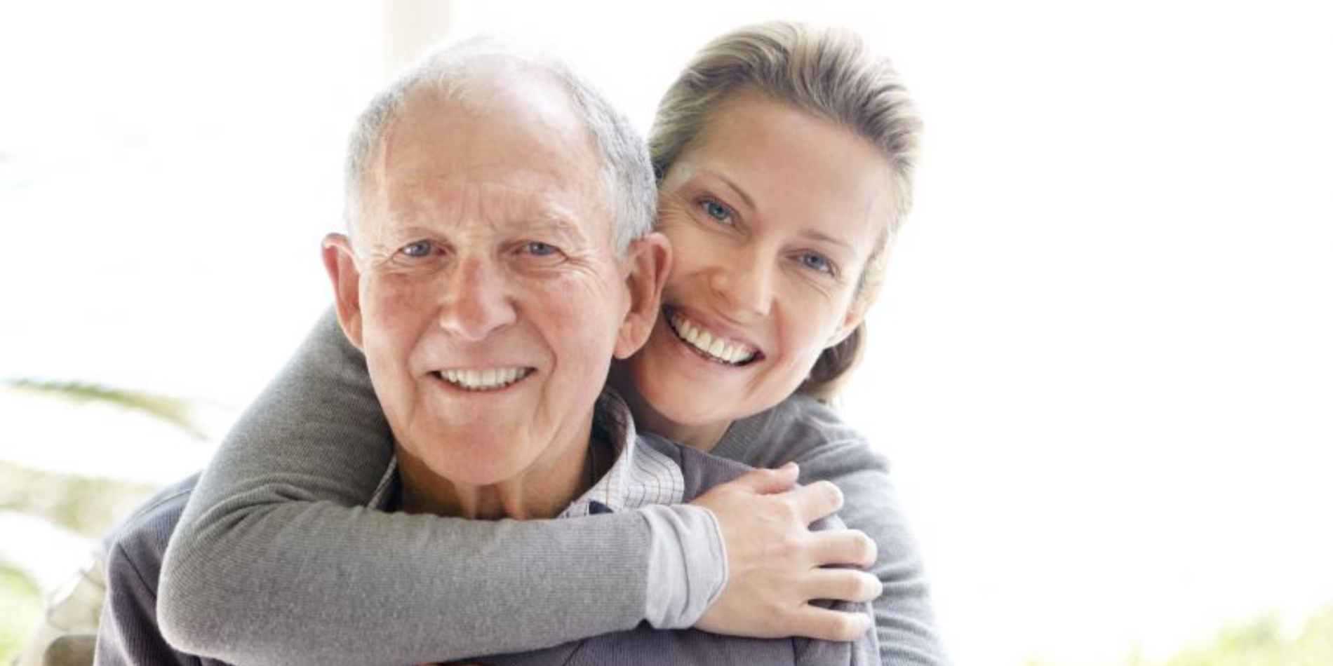 Elderly man and daughter hugging him from behind
