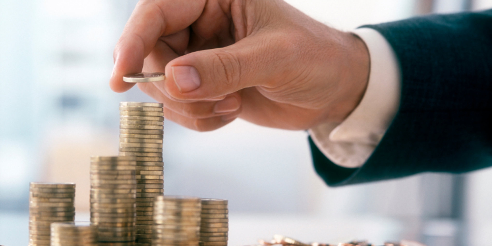 Hand placing coin on top of a stack of coins
