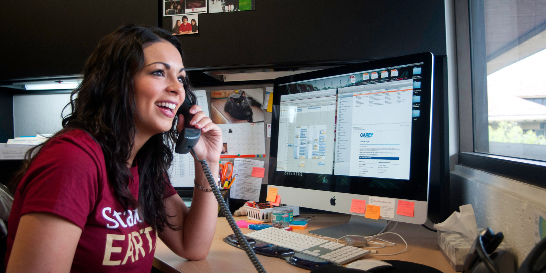 Stanford female employee on the phone at her desk in front of two monitors