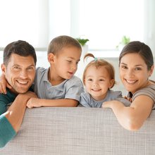 Happy family of four sitting on sofa