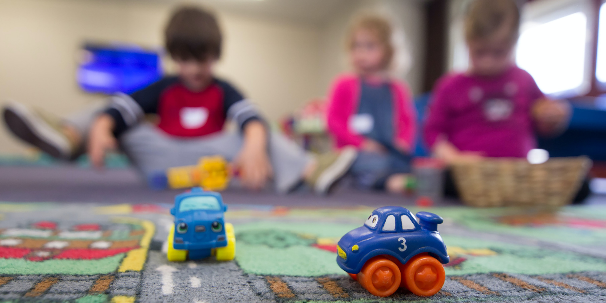 Young kids playing in a preschool play area on a road carpet
