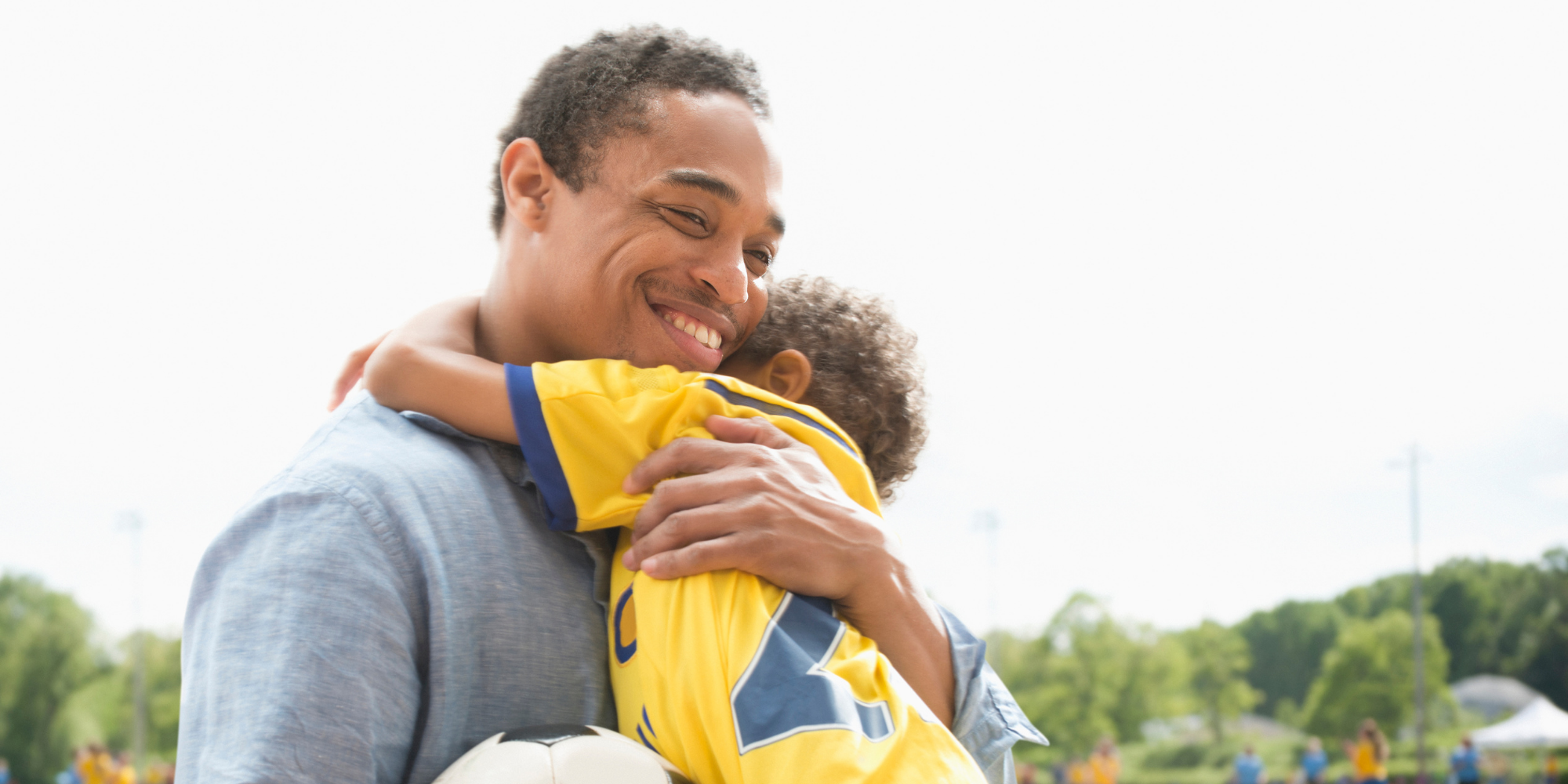 Dad holding his son at a soccer match